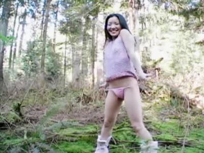Asiatin macht sich im Wald nackt